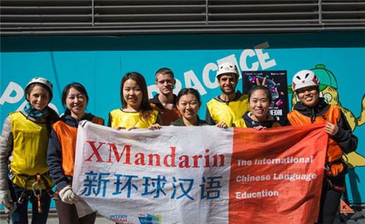 Group of international Chinese language students, chinese teachers, and our service team, holding the XMandarin flag during a rock climbing event